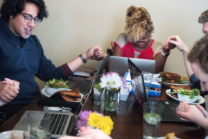 students praying around a table