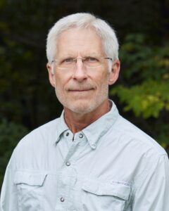 Dr. Rick Lindroth has white hair and glasses. He is wearing a pale blue button-down shirt.