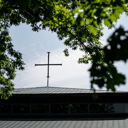 A cross on the peak of Olson Campus Center, Luther Seminary, Saint Paul, with tree branches in the foreground