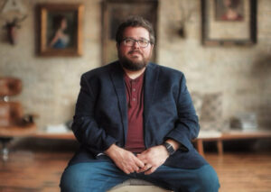 Publicity photo of theologian and podcaster Tripp Fuller sitting in an interestingly decorated room