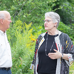 Two people conversing in a garden setting.