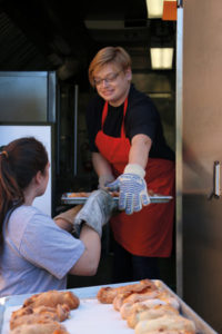 people carrying trays from ovens