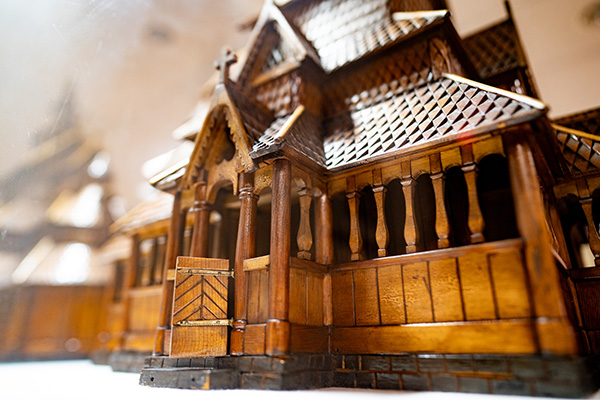 Close-up of a detailed wooden architectural model of a medieval-style building with intricate carvings and textured roof.
