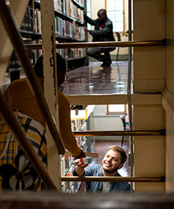 People interacting in a multi-level library setting with bookshelves.