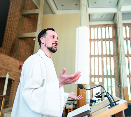 A man standing at the pulpit preaching in robes