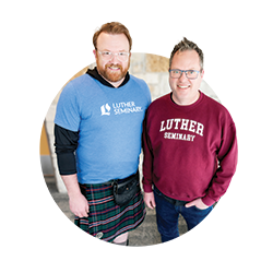Two people wearing "Luther Seminary" apparel, one in a kilt and one in a sweatshirt, standing indoors.
