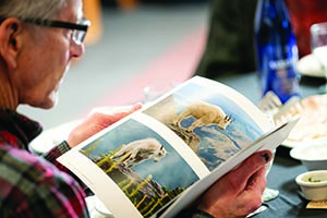 Close-up of a person reading a book featuring large color photographs of white mountain goats.